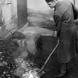 Günther Venter beim Wenden eines fertig gebrannten Lehmkuchens - das flüssige Messing verteilt sich hierbei über die Glocken